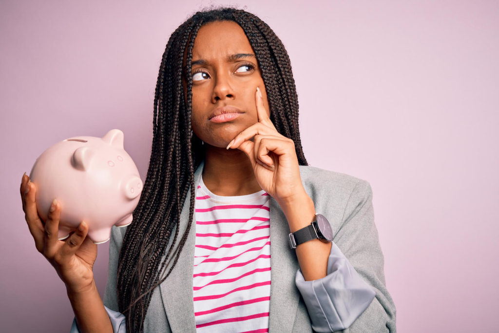 woman holding a piggy bank questioning seomthing